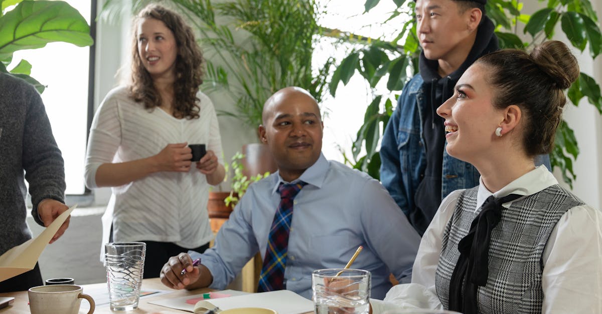 A diverse group of colleagues engaging in a collaborative meeting in a bright office with natural elements.